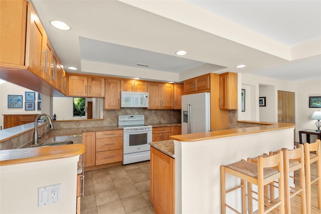 8 Braemer Rd, East Setauket, NY 11733 - kitchen featuring white appliances, a tray ceiling, a peninsula, tasteful backsplash, and recessed lighting