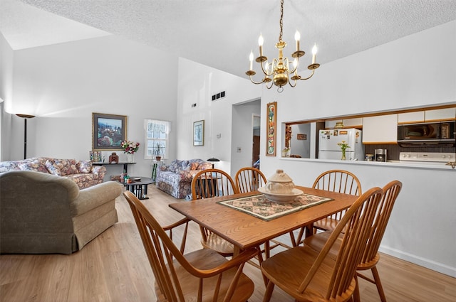 41 Millholland Dr, Fishkill, NY 12524 - dining area featuring high vaulted ceiling, a chandelier, a textured ceiling, and light wood-style floors
