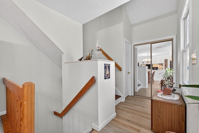 41 Millholland Dr, Fishkill, NY 12524 - hallway with light wood finished floors, an upstairs landing, a chandelier, and a textured ceiling