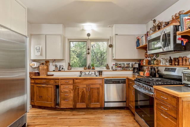5 Shore Dr, Setauket, NY 11733 - kitchen with appliances with stainless steel finishes, light wood-type flooring, open shelves, brown cabinetry, and light countertops