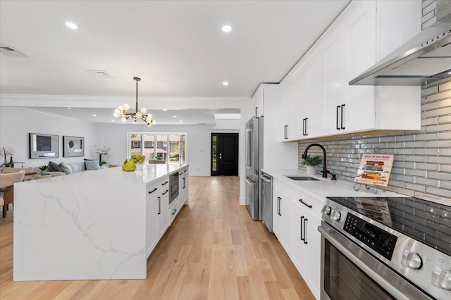 77 Bounty Ln, Jericho, NY 11753 - kitchen with stainless steel appliances, ventilation hood, light wood-style flooring, white cabinetry, and a kitchen island