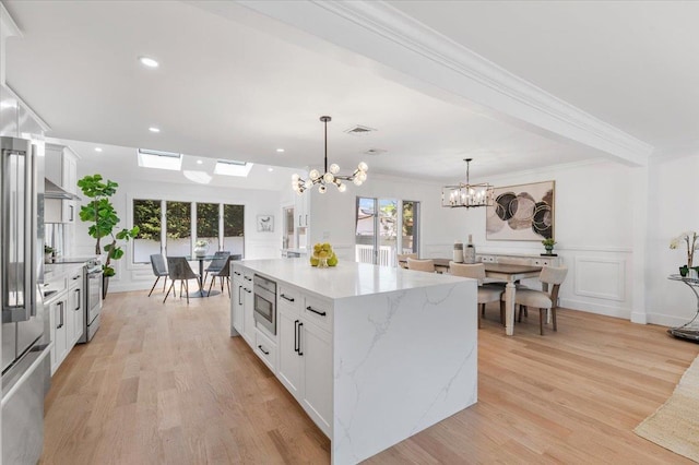 77 Bounty Ln, Jericho, NY 11753 - kitchen with a chandelier, stainless steel appliances, white cabinetry, decorative light fixtures, and light wood-type flooring