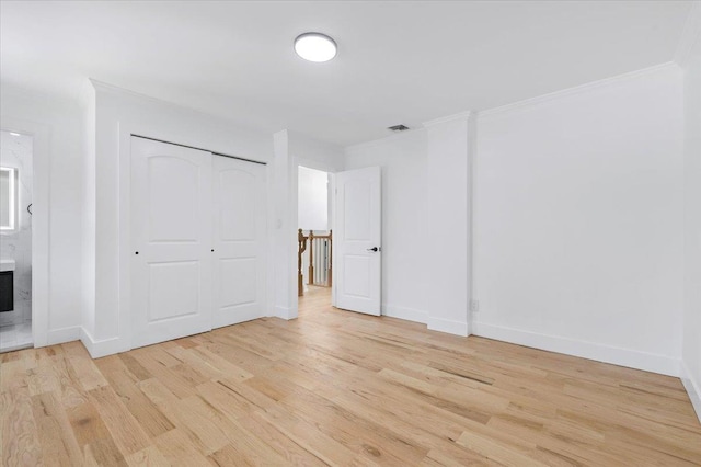 77 Bounty Ln, Jericho, NY 11753 - unfurnished bedroom featuring light wood finished floors, crown molding, ensuite bath, and a closet
