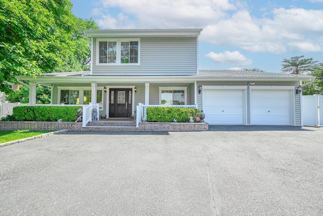 239 Walnut Rd, Glen Cove, NY 11542 - view of front facade featuring asphalt driveway, an attached garage, and a porch
