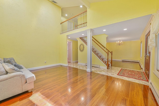 239 Walnut Rd, Glen Cove, NY 11542 - unfurnished living room with stairs, a baseboard heating unit, wood finished floors, a chandelier, and recessed lighting