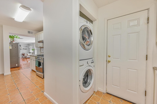 239 Walnut Rd, Glen Cove, NY 11542 - laundry area with stacked washer and clothes dryer and light tile patterned floors