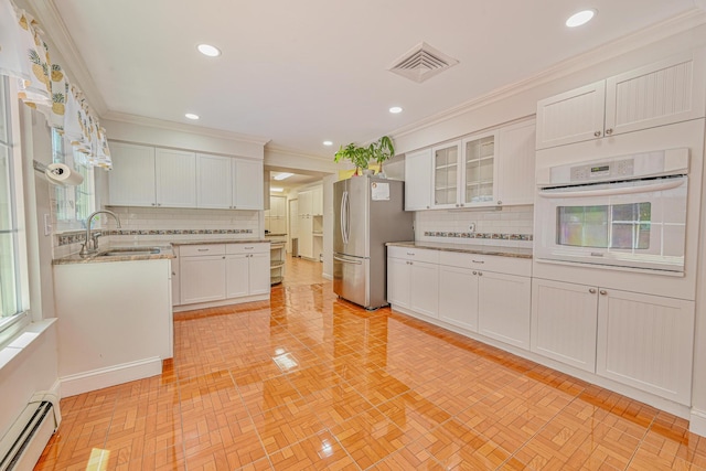 239 Walnut Rd, Glen Cove, NY 11542 - kitchen with oven, a baseboard heating unit, freestanding refrigerator, tasteful backsplash, and white cabinetry