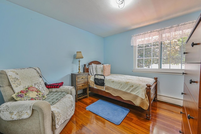 239 Walnut Rd, Glen Cove, NY 11542 - bedroom featuring a baseboard heating unit and wood finished floors
