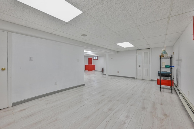 239 Walnut Rd, Glen Cove, NY 11542 - finished below grade area featuring a baseboard radiator, a drop ceiling, and light wood-style floors
