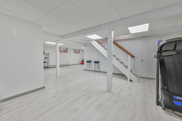 239 Walnut Rd, Glen Cove, NY 11542 - finished below grade area featuring a drop ceiling, stairs, light wood-style floors, and a baseboard heating unit