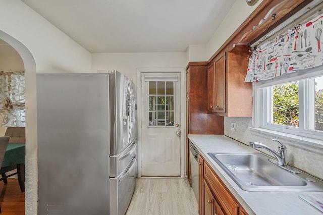 662 Rose Blvd, Baldwin, NY 11510 - kitchen featuring appliances with stainless steel finishes, light countertops, light wood-style floors, and arched walkways