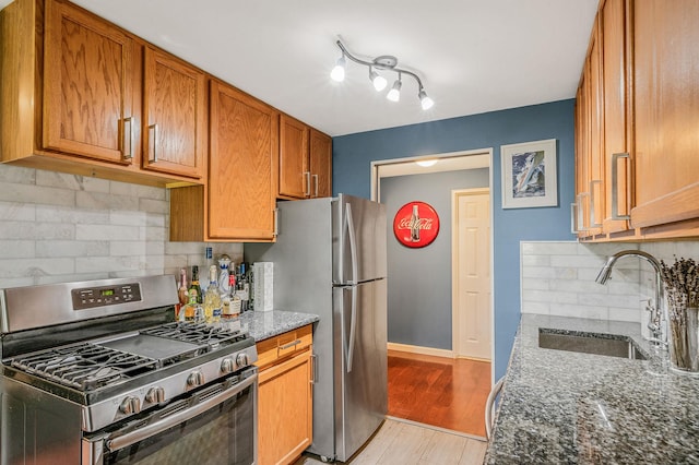 114 Jervis Ave Unit 114, Farmingdale, NY 11735 - kitchen featuring stainless steel appliances, dark stone counters, backsplash, brown cabinetry, and light wood finished floors