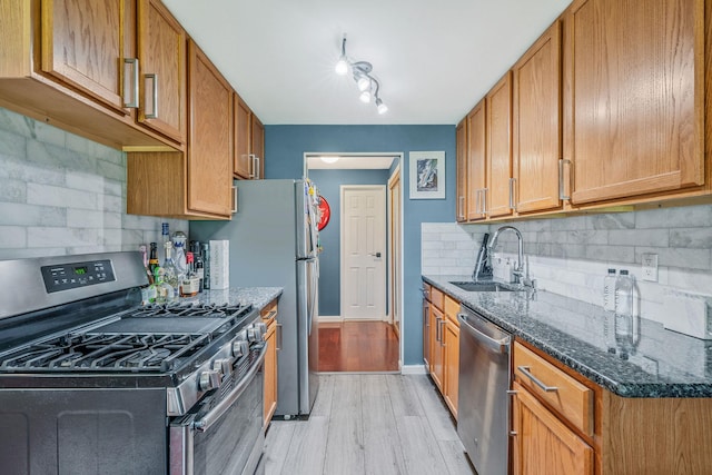114 Jervis Ave Unit 114, Farmingdale, NY 11735 - kitchen featuring stainless steel appliances, light wood-type flooring, backsplash, dark stone countertops, and brown cabinets