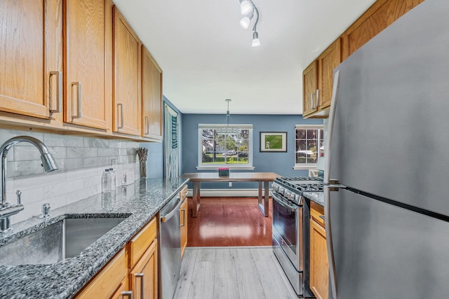 114 Jervis Ave Unit 114, Farmingdale, NY 11735 - kitchen featuring appliances with stainless steel finishes, light wood finished floors, decorative backsplash, brown cabinets, and dark stone countertops
