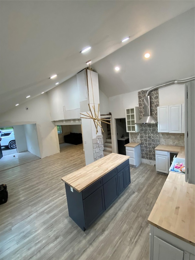 57 Chestnut St, Beach Lake, NY 13865 - kitchen featuring wood counters, wall chimney range hood, light wood-type flooring, backsplash, and high vaulted ceiling