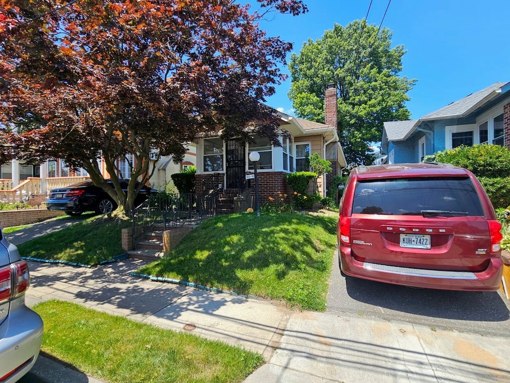 142-16 223rd St, Laurelton, NY 11413 - view of property hidden behind natural elements featuring brick siding, a front yard, and a chimney