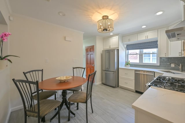 15115 25th Ave, Whitestone, NY 11357 - kitchen with appliances with stainless steel finishes, extractor fan, crown molding, light wood-type flooring, and white cabinetry