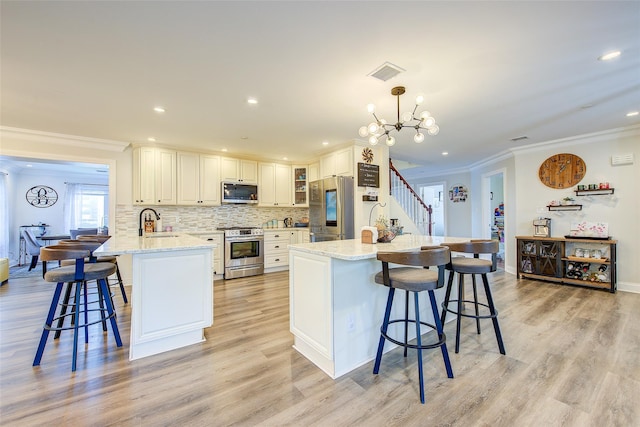 615 Pearl St, Oceanside, NY 11572 - kitchen featuring appliances with stainless steel finishes, a breakfast bar area, crown molding, light wood-type flooring, and a peninsula