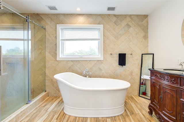 615 Pearl St, Oceanside, NY 11572 - bathroom featuring a soaking tub, a shower stall, wood finished floors, vanity, and tile walls