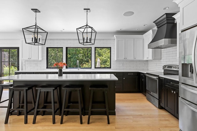 9 Guthrie Ct, East Northport, NY 11731 - kitchen with appliances with stainless steel finishes, wall chimney exhaust hood, light countertops, decorative backsplash, and white cabinetry