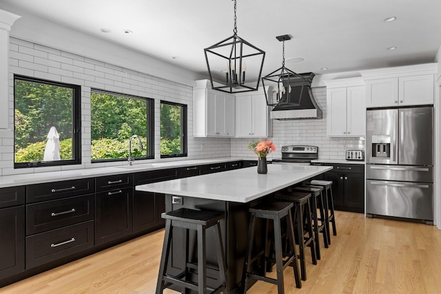 9 Guthrie Ct, East Northport, NY 11731 - kitchen featuring appliances with stainless steel finishes, wall chimney range hood, healthy amount of natural light, dark cabinetry, and recessed lighting