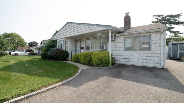 14 Lois Ln, Farmingdale, NY 11735 - bungalow-style home featuring a chimney, a front yard, a shed, and cooling unit