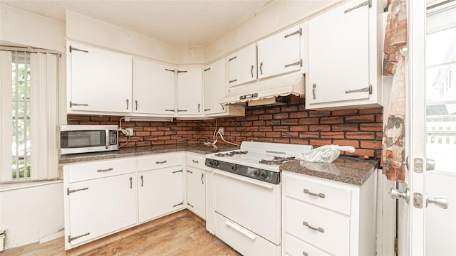 14 Lois Ln, Farmingdale, NY 11735 - kitchen featuring stainless steel microwave, under cabinet range hood, white range oven, dark countertops, and a textured ceiling