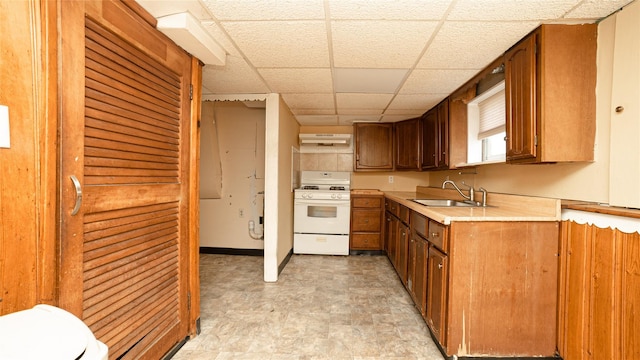 14 Lois Ln, Farmingdale, NY 11735 - kitchen with gas range gas stove, a paneled ceiling, under cabinet range hood, light countertops, and brown cabinets