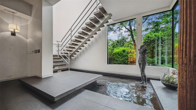 entryway with plenty of natural light, stairway, and concrete floors