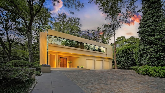 garage at dusk with decorative driveway