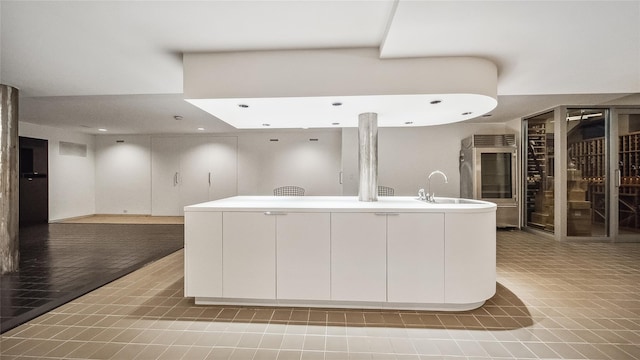 kitchen with white cabinetry, recessed lighting, open floor plan, light countertops, and a kitchen island with sink
