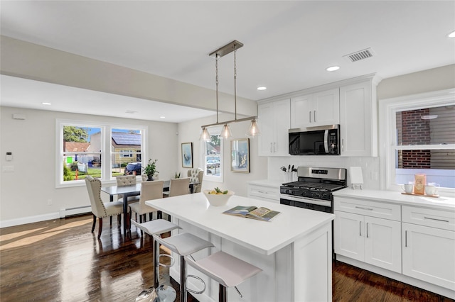 10 Branch Pl, Roosevelt, NY 11575 - kitchen with stainless steel appliances, a baseboard heating unit, a kitchen island, dark wood-type flooring, and white cabinets