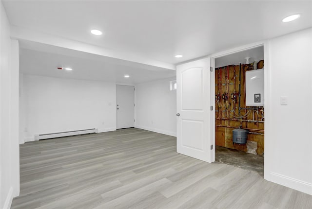10 Branch Pl, Roosevelt, NY 11575 - spare room with a baseboard radiator, tankless water heater, light wood-style floors, and recessed lighting