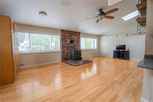 110 Roxbury Dr, Commack, NY 11725 - unfurnished living room with a wood stove, ceiling fan, vaulted ceiling, light wood-style floors, and a skylight