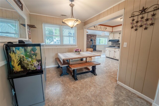 110 Roxbury Dr, Commack, NY 11725 - dining space with crown molding, a wood stove, wood walls, and light floors