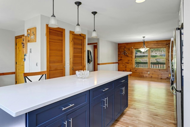 354 Sunset Hill Rd E, Fishkill, NY 12524 - kitchen with blue cabinets, freestanding refrigerator, light countertops, light wood-style floors, and hanging light fixtures