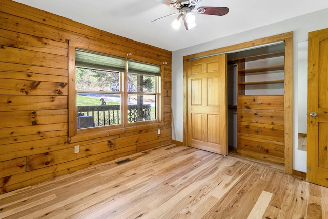 354 Sunset Hill Rd E, Fishkill, NY 12524 - unfurnished bedroom featuring light wood-type flooring, a closet, wood walls, and ceiling fan