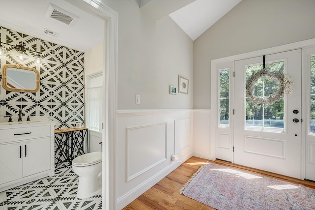 206 Brooksite Dr, Smithtown, NY 11787 - foyer entrance featuring a wainscoted wall, vaulted ceiling, light wood-style floors, and a decorative wall