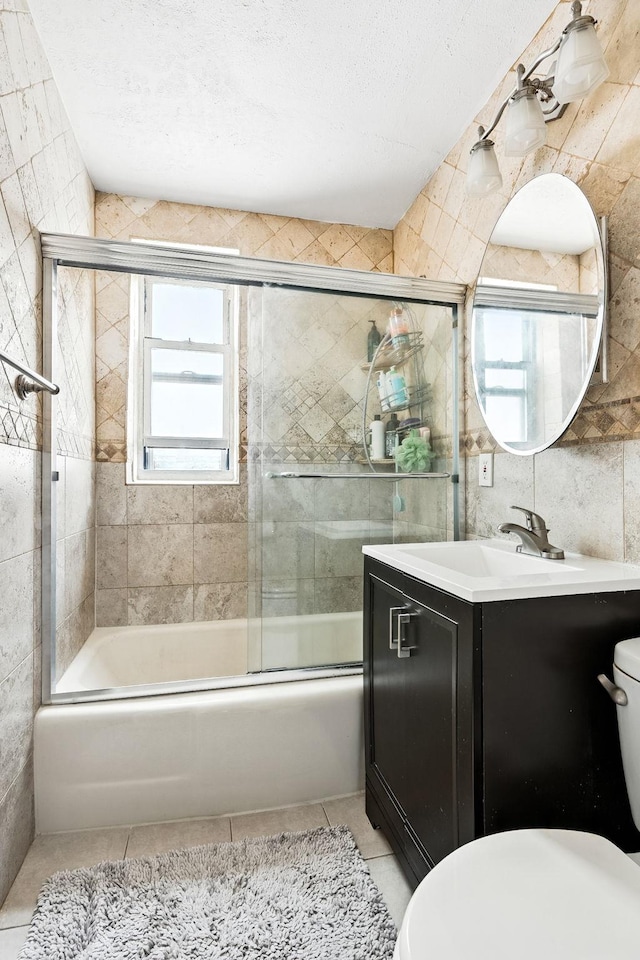 4265 Webster Ave Unit 6A, Bronx, NY 10470 - bathroom with tile patterned flooring, vanity, tile walls, combined bath / shower with glass door, and a textured ceiling