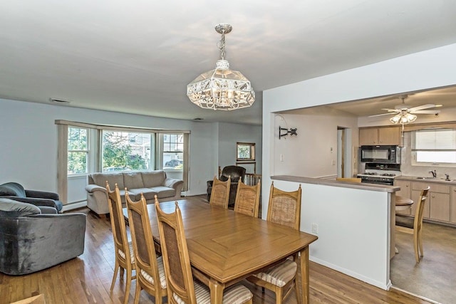 46 Pine St, Oceanside, NY 11572 - dining space featuring a chandelier, light wood-style floors, a baseboard heating unit, and a ceiling fan