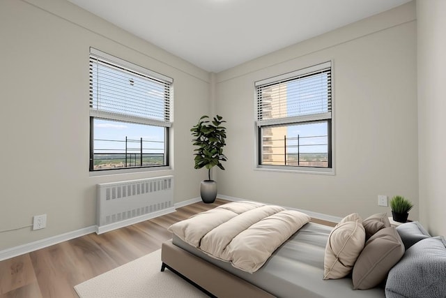 99-72 66th Rd Unit 9B, Rego Park, NY 11374 - bedroom with radiator heating unit, multiple windows, and wood finished floors