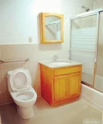 35-06LEAVITTST Leavitt St Unit 7F, Flushing, NY 11354 - full bath with vanity, enclosed tub / shower combo, wainscoting, and tile patterned flooring