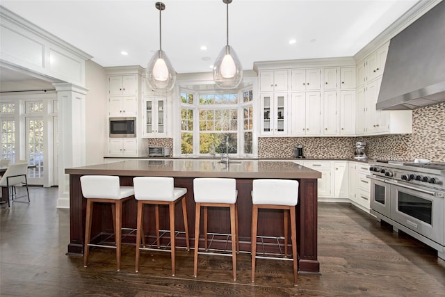 5 Sutton Farm Dr, Chappaqua, NY 10514 - kitchen featuring wall chimney range hood, stainless steel appliances, tasteful backsplash, glass insert cabinets, and healthy amount of natural light