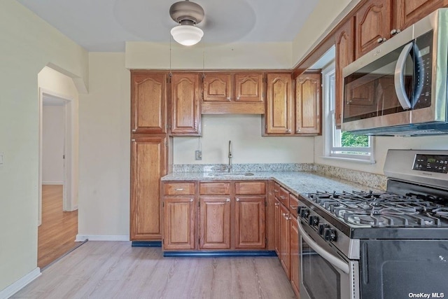 216 Raff Ave, Mineola, NY 11501 - kitchen featuring stainless steel appliances, light wood-style flooring, and brown cabinetry