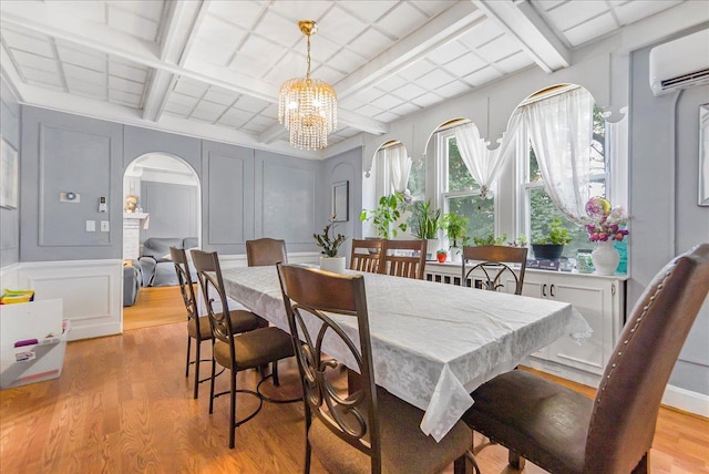 7 Wellesley Ave, Yonkers, NY 10705 - dining area featuring a decorative wall, a wall unit AC, arched walkways, light wood finished floors, and a chandelier