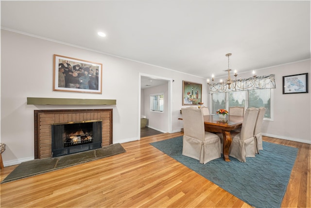 1942 Lilac Dr, Westbury, NY 11590 - dining space with crown molding, a chandelier, wood finished floors, a brick fireplace, and recessed lighting