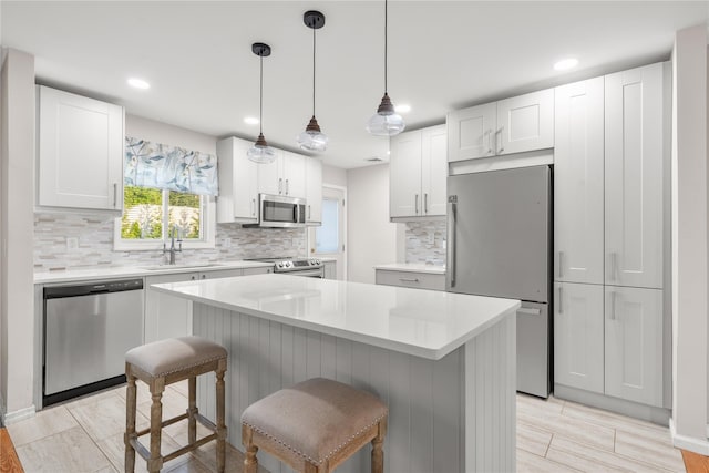 1942 Lilac Dr, Westbury, NY 11590 - kitchen with appliances with stainless steel finishes, a breakfast bar, backsplash, light countertops, and recessed lighting
