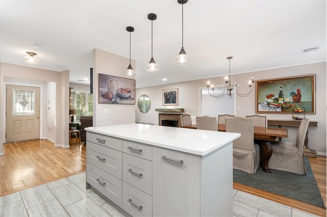 1942 Lilac Dr, Westbury, NY 11590 - kitchen with light countertops, light wood finished floors, a center island, and pendant lighting