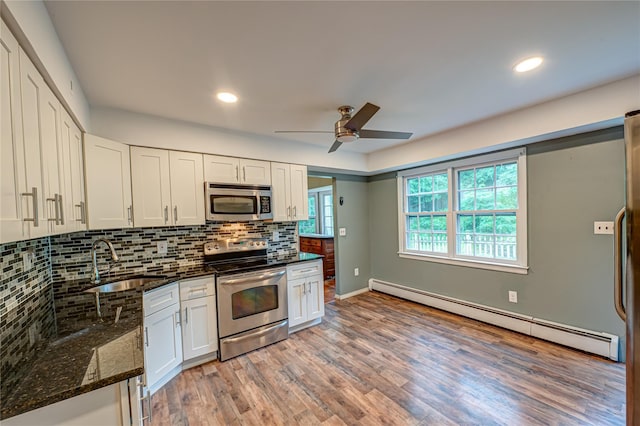 10 Valentine Rd, Shoreham, NY 11786 - kitchen featuring appliances with stainless steel finishes, a baseboard heating unit, dark stone counters, white cabinets, and recessed lighting