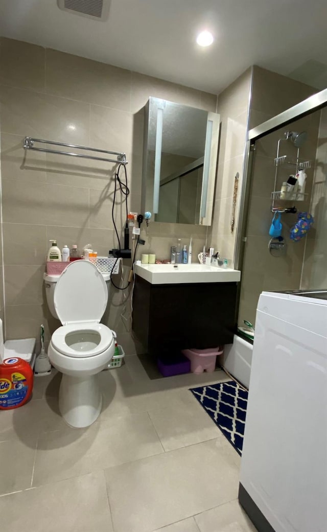 158-15 Union Tpke Unit 2D, Fresh Meadows, NY 11366 - bathroom with tile walls, tile patterned floors, vanity, bath / shower combo with glass door, and washer / clothes dryer
